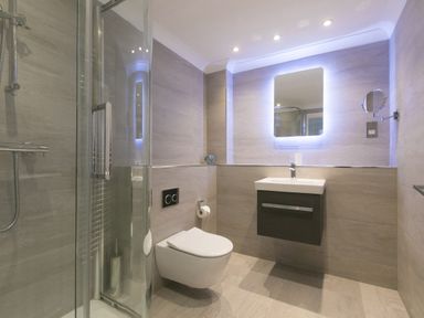 A bathroom with a shower enclosure toilet floating sink and an illuminated mirror at Wavetop in Carbis Bay