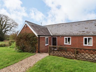 A brick house with a tiled roof a gravel path and green lawn at The Old Dairy in Whitchurch Canonicorum near Charmouth