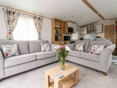 A living room with two gray sofas and a wooden coffee table with flowers at Silverdale View in East Heslerton near Sherburn