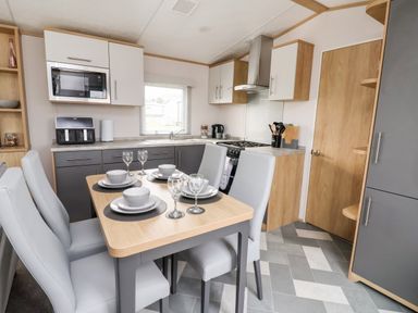 A kitchen with dining table set for four and grey chairs at Silverdale View in East Heslerton near Sherburn