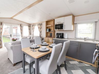 An open plan dining and living area with a table set for four chairs and a kitchen in Silverdale View East Heslerton near Sherburn