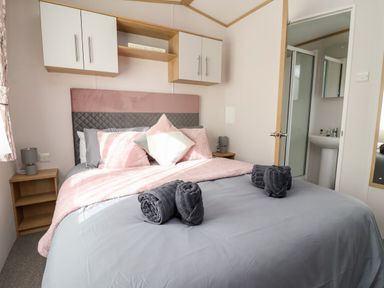 A bedroom with a double bed pillows and folded towels bedside tables and an en suite bathroom at Silverdale View East Heslerton near Sherburn