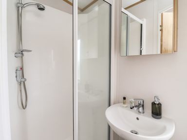 A bathroom with a shower enclosure and a sink with toiletries at Silverdale View East Heslerton near Sherburn