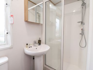 A bathroom with a sink and mirror cabinet next to a shower enclosure at Silverdale View in East Heslerton near Sherburn