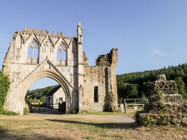 A stone archway and ruins near a small building and forest in the background at Silverdale View in East Heslerton near Sherburn