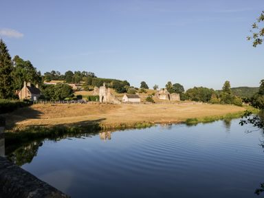 A river with reflections of trees and ruins on the bank at Silverdale View in East Heslerton near Sherburn