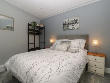 A bedroom with a bed a bedside table with a lamp a black rack with hangers and a mirror on the wall at Myrtle Cottage in St Brides-Super-Ely