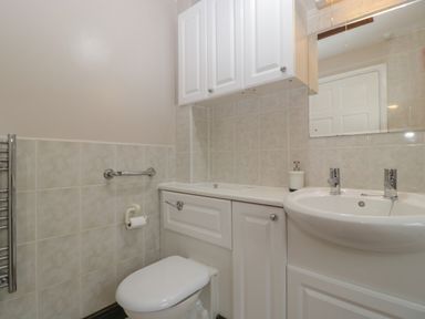 A bathroom with a toilet a sink a wall-mounted cabinet and a mirror at Myrtle Cottage in St Brides-Super-Ely