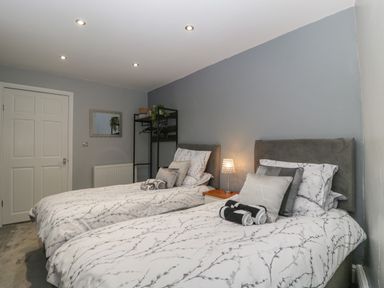 A bedroom with two single beds bedside table and open wardrobe at Myrtle Cottage in St Brides-Super-Ely