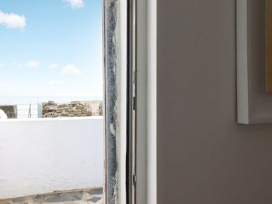 A partially open door showing a white wall and stone wall outside at Waves End in Mevagissey