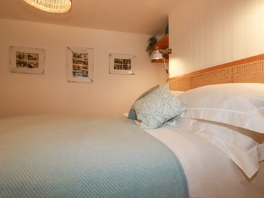 A bedroom with a bed with blue and white patterned pillows and a light blue blanket with framed pictures on the wall