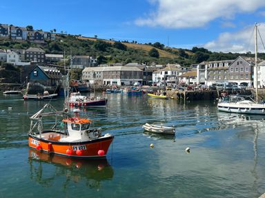 A harbor with boats and buildings on a hillside at Waves End in Mevagissey