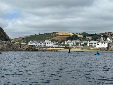 A coastal village with houses on the shore hills and rocky areas visible in Mevagissey