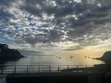 A view of a calm sea with boats and a cloudy sky at Waves End in Mevagissey
