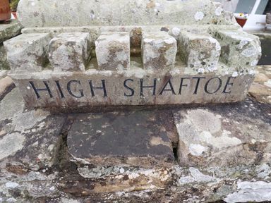 A carved stone with the words High Shaftoe on a stone wall at High Shaftoe in Ponteland