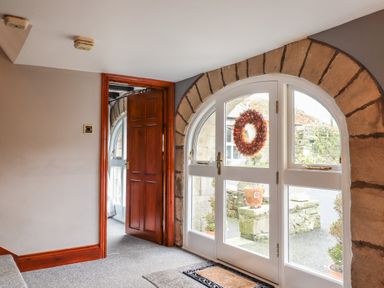 An entryway with a wooden door mirror and glass doors with a wreath at High Shaftoe in Ponteland