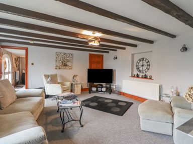 A living room with sofas armchair television and exposed wooden beams at High Shaftoe in Ponteland