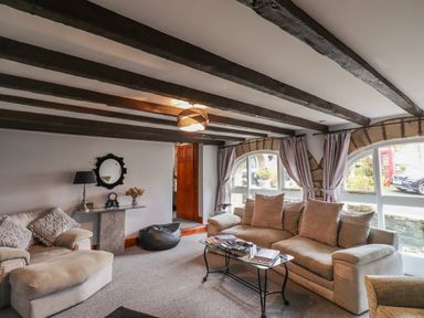 A living room with sofas a glass coffee table and visible wooden ceiling beams at High Shaftoe in Ponteland