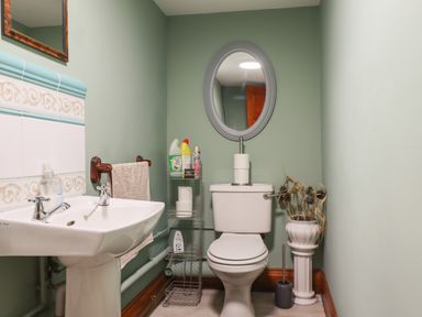 A bathroom with a toilet sink mirror and cleaning supplies at High Shaftoe in Ponteland