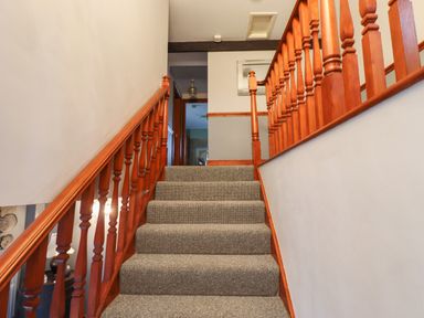 A carpeted staircase with wooden handrails leading to a hallway at High Shaftoe in Ponteland