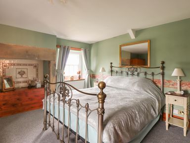 A bedroom with a metal bed frame bedside tables lamps and a large mirror on the wall at High Shaftoe in Ponteland