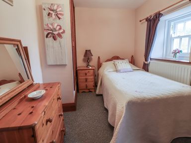 A small bedroom with a single bed wooden furniture and a window with curtains at High Shaftoe in Ponteland