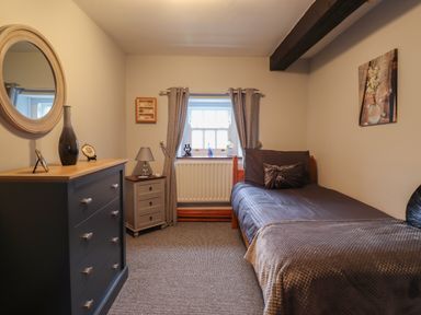 A bedroom with a single bed a chest of drawers a window with curtains and a bedside table at High Shaftoe in Ponteland