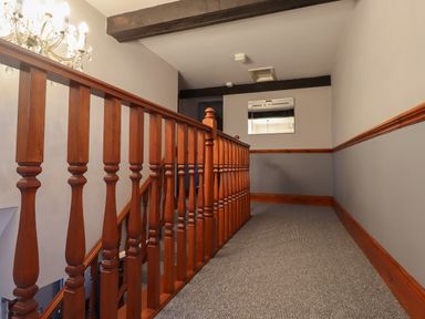 A carpeted hallway with wooden railing and grey walls with a mirror at High Shaftoe in Ponteland