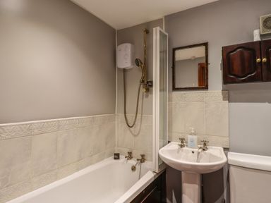 A bathroom with bathtub shower sink mirror and wooden cabinet at High Shaftoe in Ponteland