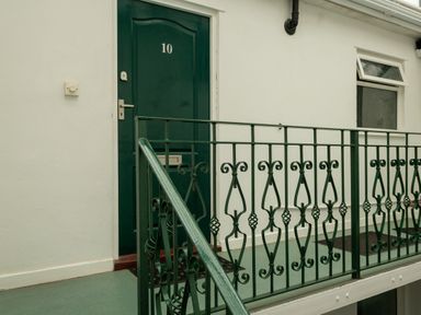 A green door with the number 10 and a decorative green metal railing on a balcony at The Gables Penthouse in Bournemouth