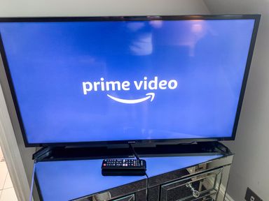 A television displaying prime video logo on a mirrored cabinet with a remote control on top at The Gables Penthouse in Bournemouth