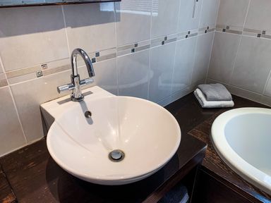 A bathroom sink with a chrome faucet and folded towels on a wooden countertop at The Gables Penthouse in Bournemouth