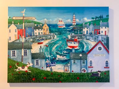 A painting of a seaside village with boats in the harbor a lighthouse houses a dog and a cat on grass at The Gables Penthouse in Bournemouth
