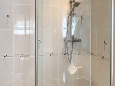 A tiled shower area with a handheld shower head and glass door at The Gables Penthouse in Bournemouth