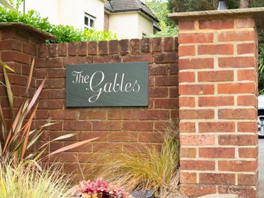 A brick wall with a sign saying The Gables surrounded by plants at The Gables Penthouse in Bournemouth