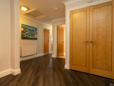 A hallway with wooden double doors a painting radiator and three additional doorways at The Gables Penthouse in Bournemouth