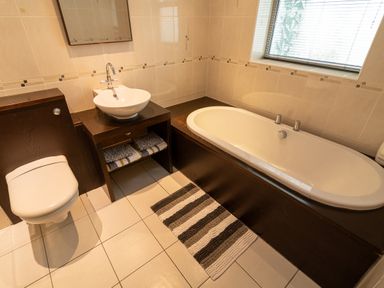 A bathroom with a toilet sink and bathtub with a striped rug on the floor at The Gables Penthouse in Bournemouth