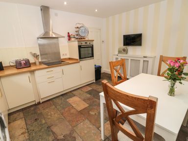 A kitchen with wooden chairs and a white table with flowers on it at Tyne View Cottage in Bellingham