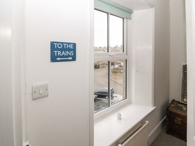 A window with a white sill below and a blue sign on the wall reading to the trains pointing left at Tyne View Cottage in Bellingham