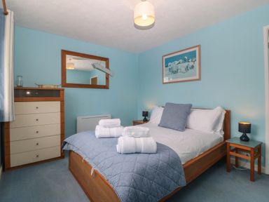 A bedroom with a bed and dresser at Wingelock Rhosneigr
