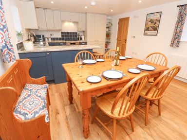 A kitchen and dining area with a wooden table set with plates and wine at The Byre in Carrshield near Allendale