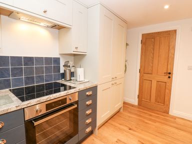 A kitchen with a stovetop oven blue tile backsplash and wooden door at The Byre in Carrshield near Allendale