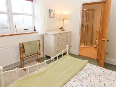 A bedroom with a bed a chest of drawers a wooden towel rack and an en suite bathroom at The Byre in Carrshield near Allendale