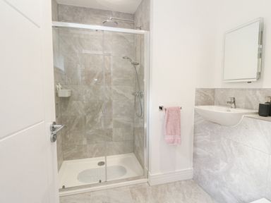 A bathroom with a glass enclosed shower and a sink with a mirror above at Coorie In in Aberfeldy