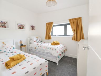 A bedroom with two single beds yellow towels and curtains and animal pictures on the wall at Coorie In in Aberfeldy