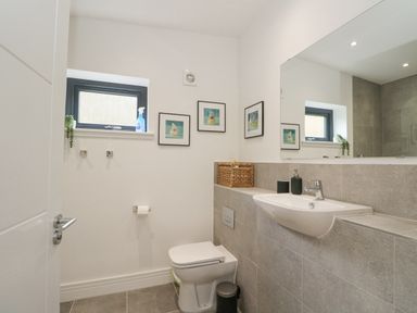 A bathroom with a toilet sink mirror and small windows at Coorie In in Aberfeldy