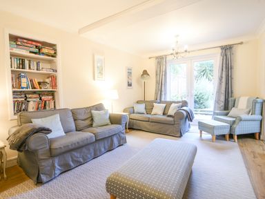 A living room with two sofas an armchair a bookshelf and glass doors at The Old Lace Shop in Beer