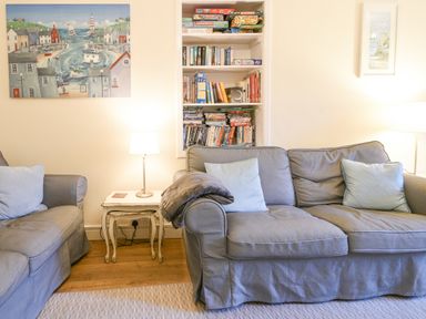 A living room with two gray sofas and a side table with a lamp between them at The Old Lace Shop in Beer