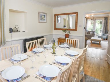 A dining room with a table set for six and a doorway to a sitting room at The Old Lace Shop in Beer