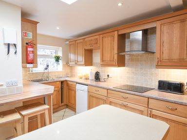 A kitchen with wooden cabinets a stove a toaster and a countertop at The Old Lace Shop in Beer